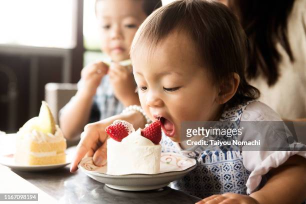 a girl who opens her mouth and tries to eat strawberries - erdbeerkuchen stock-fotos und bilder