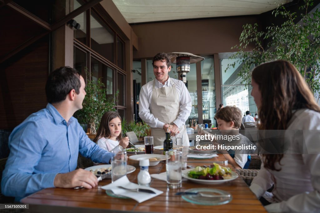 Männliche Gäste mit seiner Familie genießen eine Mahlzeit im Hotelrestaurant und bestellen etwas an freundlichen Kellner