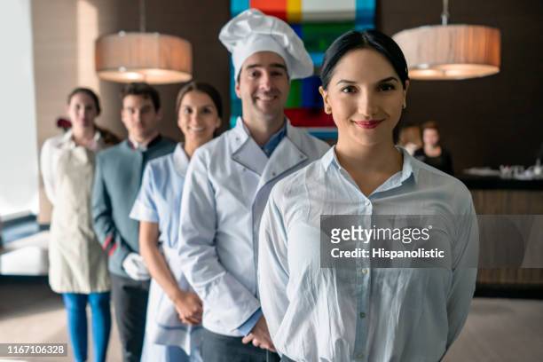 高級ホテルのプロのホテルスタッフは、女性マネージャーの後ろに立ってカメラに向かってすべての直面しています - ホテルマン ストックフォトと画像