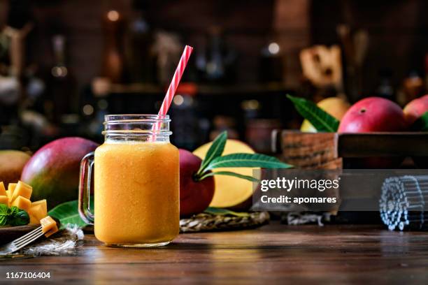 mango smoothie sap en fruit un drinken glas op houten tafel in rustieke keuken - mango juice stockfoto's en -beelden