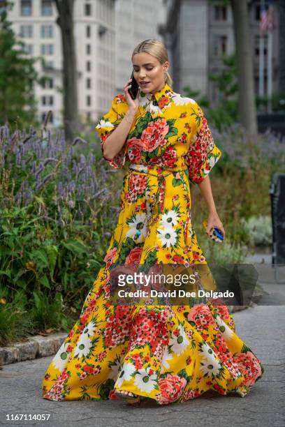 Guest wearing a yellow flower pattern dress attends the Carolina Herrera show during New York Fashion Week at the Garden of the Battery on September...