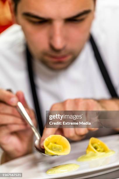 a close-up of a chef making a decoration from a ravioli on a plate - molecular gastronomy stock pictures, royalty-free photos & images