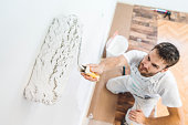 Professional painter holding a paint roller soaking in white wall paint