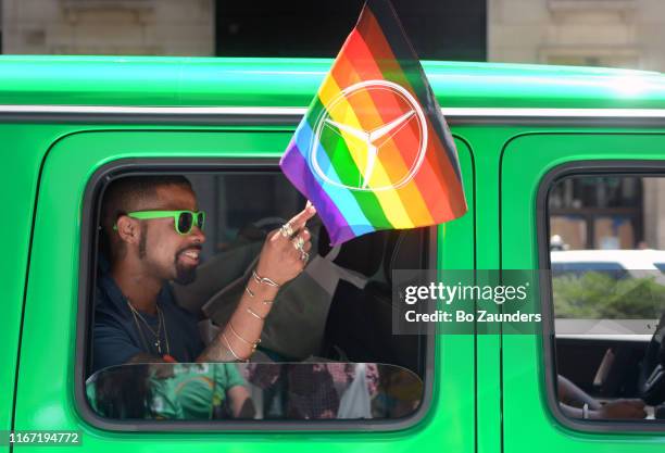 young man with green sunglasses in a green car, waving a rainbow flag at nyc pride march on june 30, 2019, in new york city. - car parade stock pictures, royalty-free photos & images