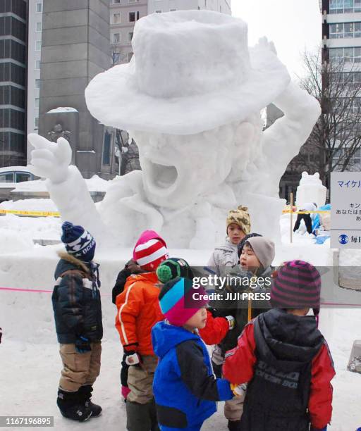 Children admire a snow sculpture of tha late king of pop Michael jackson at the 61st Snow Festival in Sapporo in Hokkaido, northern Japan on February...