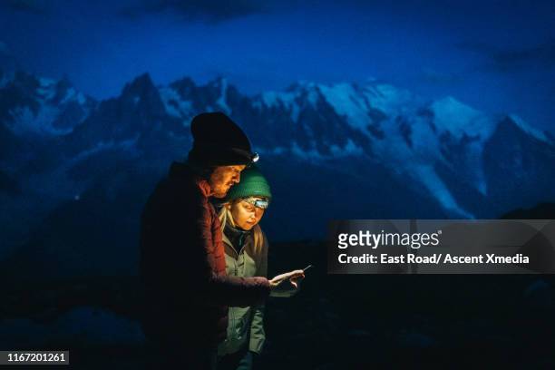 hikers explore mountain landscape, at dusk - mann auf berg mit smartphone stock-fotos und bilder