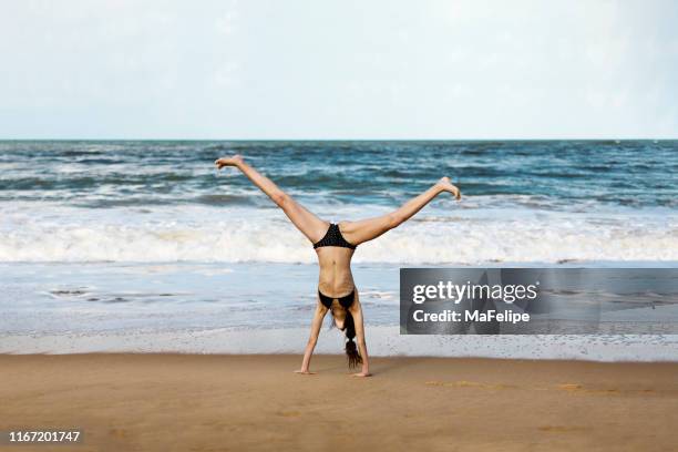 teenage girl doing a cartwheel at the beach - cartwheel stock pictures, royalty-free photos & images