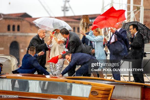 Queen Mathilde of Belgium embarks on a boat as umbrellas go flying in bad weather, after a visit of the Queen to the 58th Venice Biennale Arte,...