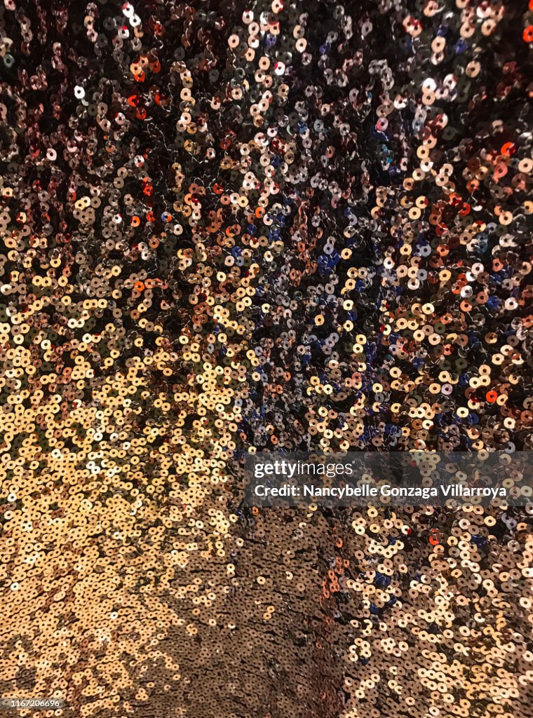 Gold, black, Brown, and orange coloured Sequined fabric swatch.