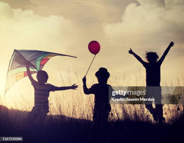 children with kite running at sunset silhouette - old brother stock pictures, royalty-free photos & images