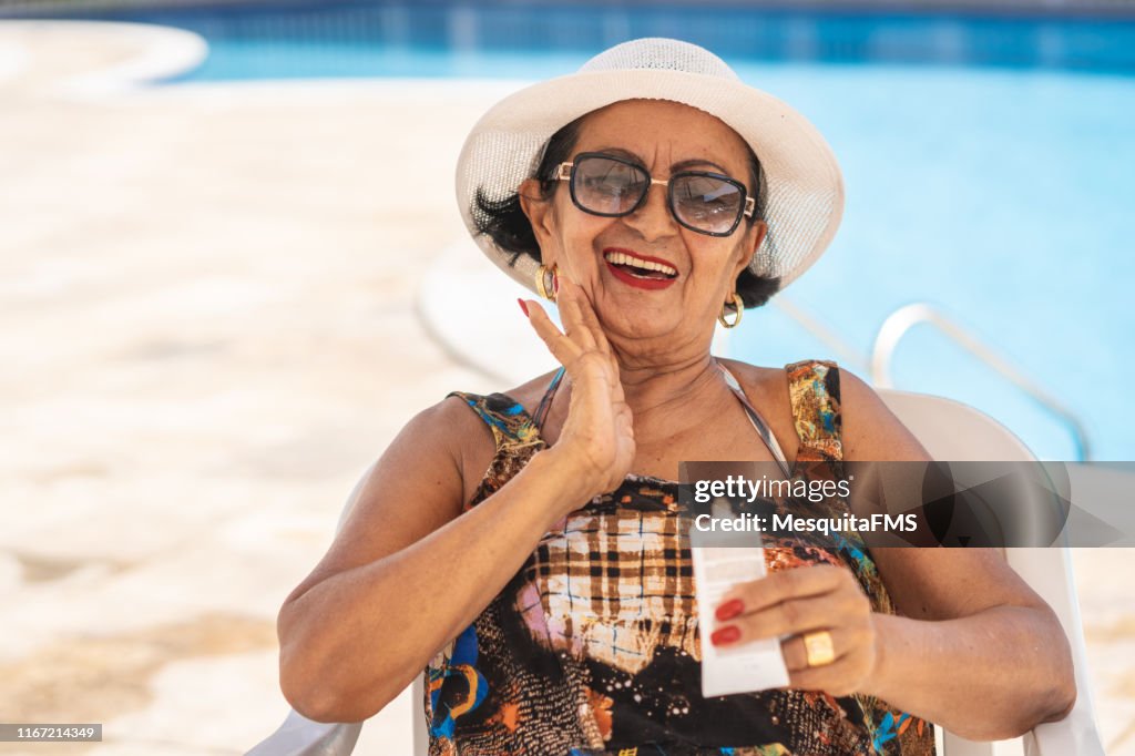 Mature woman applying suntan lotion