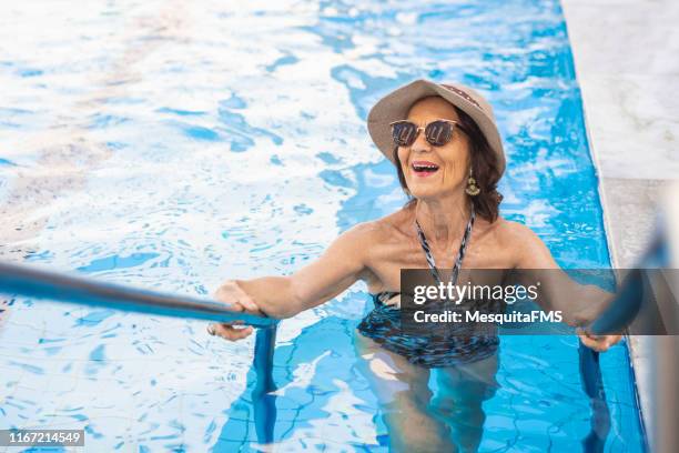 reife frau genießen sonnigen tag im luxus-hotel pool - old woman in swimsuit stock-fotos und bilder