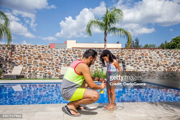 latino dad applying sun cream to his daughter - hot mexican girls stock pictures, royalty-free photos & images