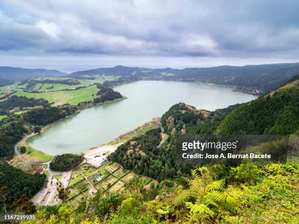 lake of volcanic landscape surrounded by mountains seen from an elevated viewpoint in spring in sao miguel island, azores islands, portugal. - furnas valley stock pictures, royalty-free photos & images