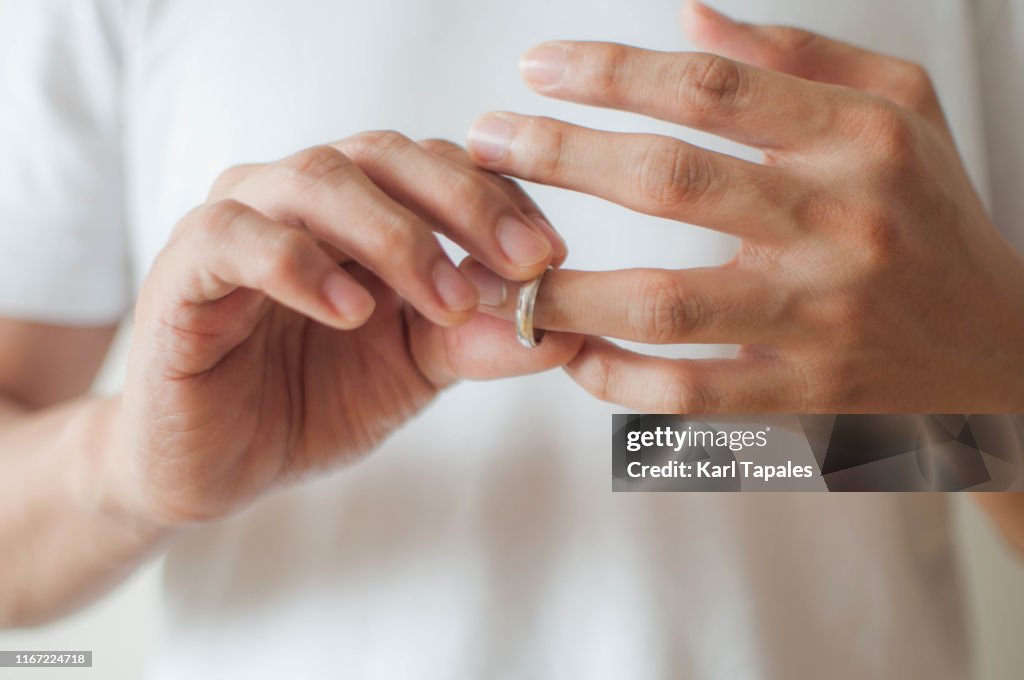 A young man is removing his wedding ring a concept of relationship difficulties