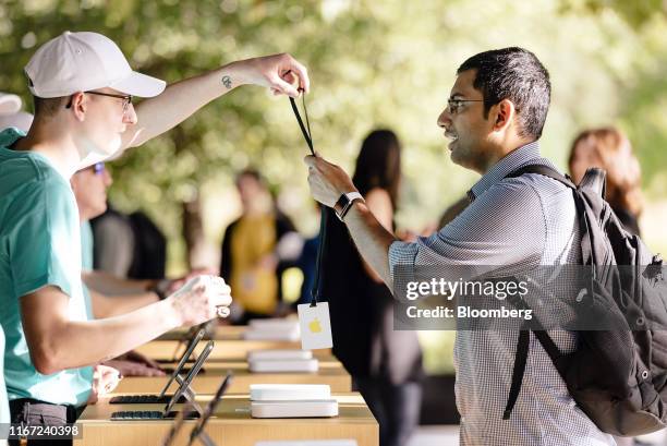 An employee hands a badge to an attendee at a check-in kiosk ahead of an Apple Inc. Event at the Steve Jobs Theater in Cupertino, California, U.S.,...