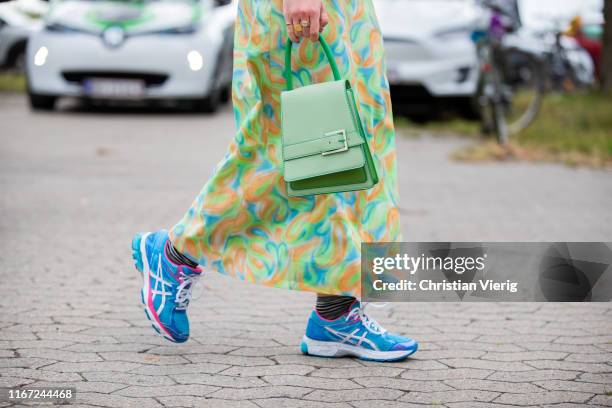 Guest is seen wearing dress with print, green bag, sneakers outside Munthe during Copenhagen Fashion Week Spring/Summer 2020 on August 07, 2019 in...