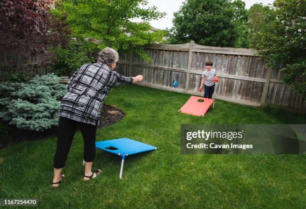 grandmother and grandson playing corn hole game in a backyard. - corn hole stock pictures, royalty-free photos & images