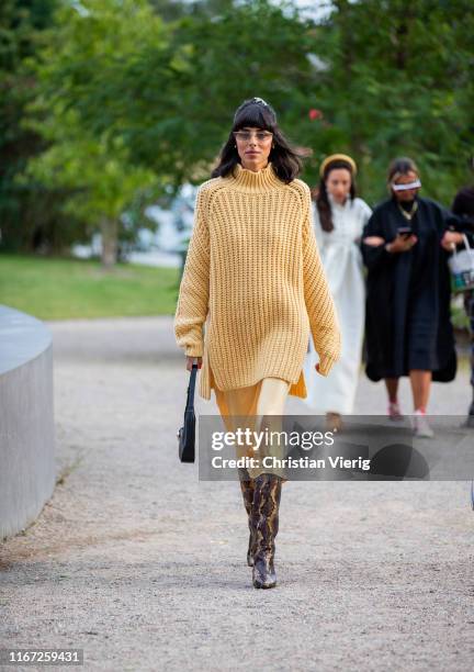 Babba Rivera is seen wearing yellow oversized knit, silk dress, boots with snake print outside Samsøe & Samsøe during Copenhagen Fashion Week...