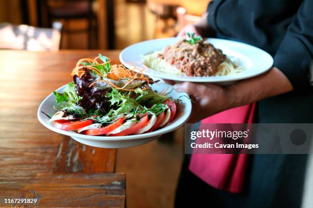 server poses with the dishes in the restaurant - woodland cafe stock pictures, royalty-free photos & images