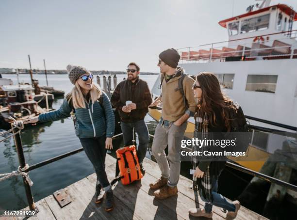 four young adult friends wait on the waterfront in portland, maine - portland maine stock-fotos und bilder