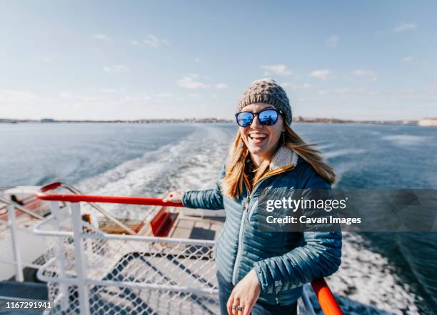 a young woman in a hat smiles while riding a ferry in portland maine - メイン州 ポートランド ストックフォトと画像