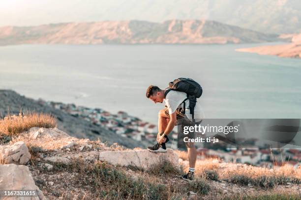 young traveler tying a shoe on the hill by the ocean - croatia tourist stock pictures, royalty-free photos & images