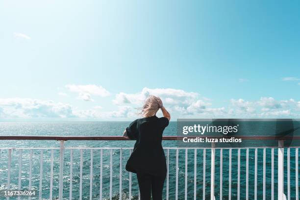 a woman with tattoos is traveling by ferry on her vacation - railings stock pictures, royalty-free photos & images