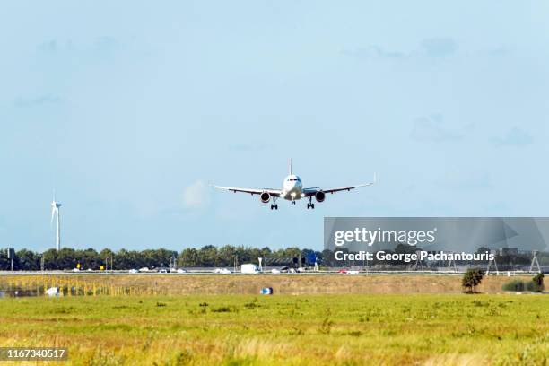 an airplane landing over a busy highway - windrad energie stockfoto's en -beelden