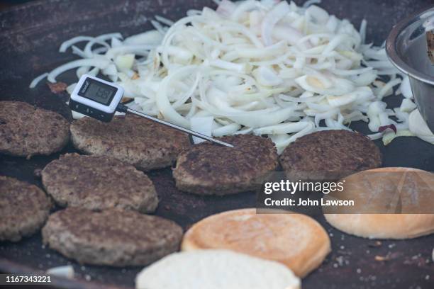 hamburgers with food thermometer and onions cooking on a griddle - burger grill stockfoto's en -beelden