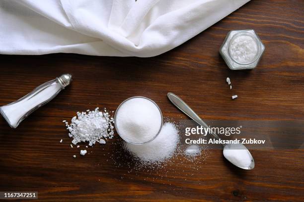 natural, organic, sea, white salt in a spoon, in a cup, in a salt shaker, poured on a wooden table. next to the linen towel. the concept of cooking healthy food, cosmetology. selective focus - zout smaakstof stockfoto's en -beelden
