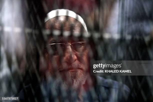 Egyptian Muslim Brotherhood Supreme Guide Mohamed Badie is seen behind bars during a verdict and sentencing session of a retrial for him and other...