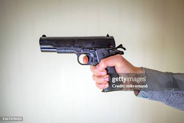 close-up of hands holding gun - handgun foto e immagini stock