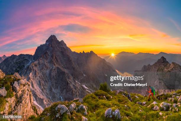 bergfotograf bei sonnenuntergang mit blick auf watzmann und gipfelkreuz des großen hundstods - bavarian alps stock-fotos und bilder