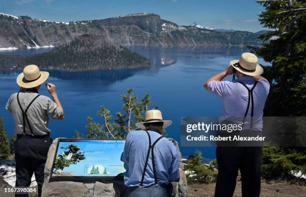 Amish men touring the American West enjoy the view of Crater Lake from a scenic overlook on the lake's rim. The lake, a water-filled caldera of an...