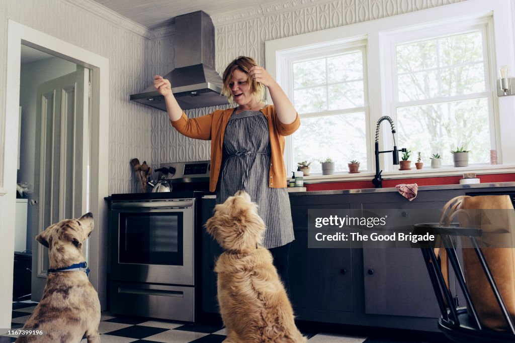 Woman feeding treats to dogs in kitchen