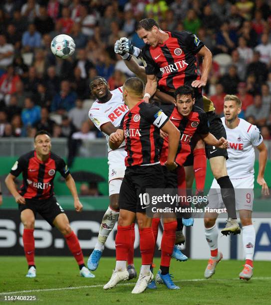 Anthony Modeste of 1. FC Koeln jumps for a header with Benedikt Roecker of SV Wehen Wiesbaden during the DFB Cup first round match between SV Wehen...