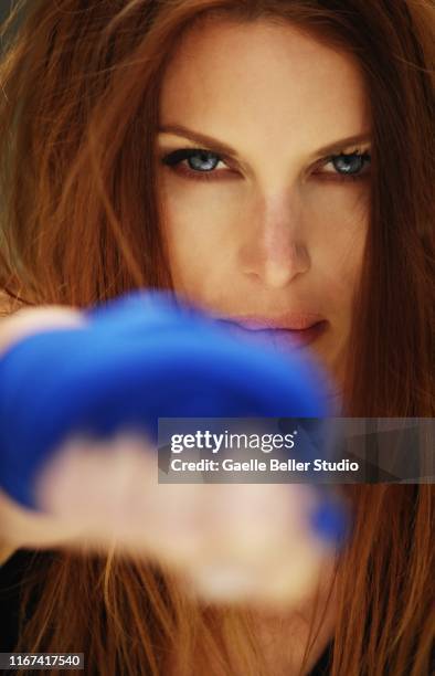 redhead woman boxer throwing a punch with blue boxing wrap on her hands - smokey eyeshadow foto e immagini stock