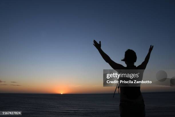 woman watching the sunset from the duna do pôr do sol (sunset dune). jericoacoara, ceará, brazil - pôr do sol fotografías e imágenes de stock