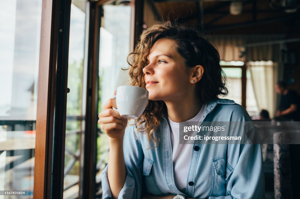 Lachende kalme jonge vrouw die koffie drinkt
