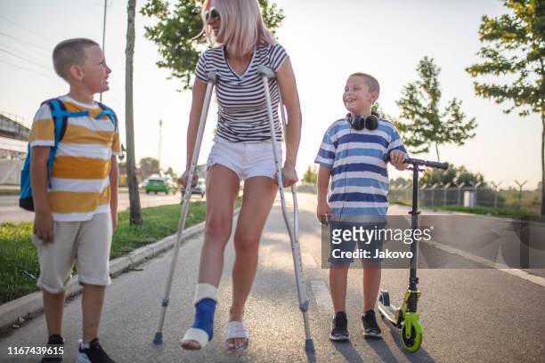 mother with her sons walking using crutches - broken leg stock pictures, royalty-free photos & images