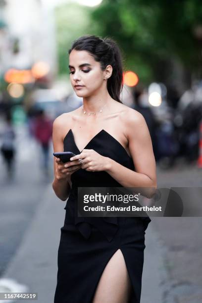 Guest wears a black off-shoulder side-slit dress, outside the "Scandal A Paris" : Jean-Paul Gaultier's New Fragance Launch Dinner Party At Lassere on...