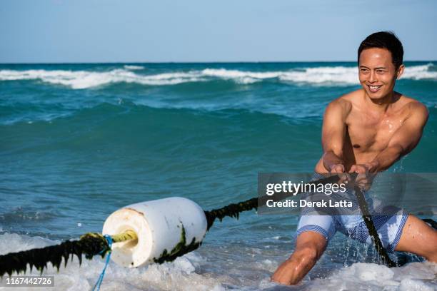 atractive confident asian man playing tug-of-war in the water. - portrait atractive man stock pictures, royalty-free photos & images