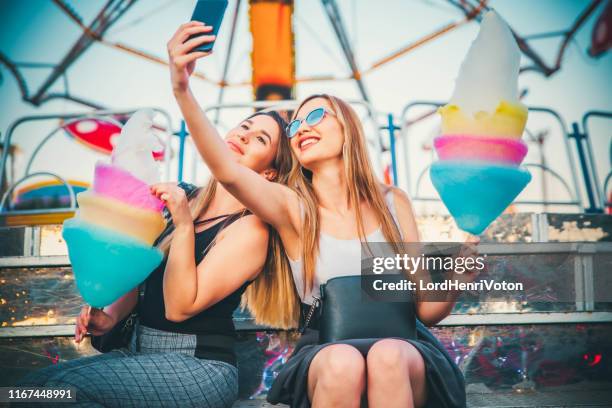 women at the amusement park with cotton candy taking selfie - festival selfie stock pictures, royalty-free photos & images