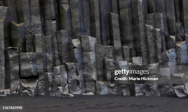 basalt columns created when lava hardens in a famous tourist destination located on the volcanic beach of vik in southern iceland. - obsidian stock-fotos und bilder