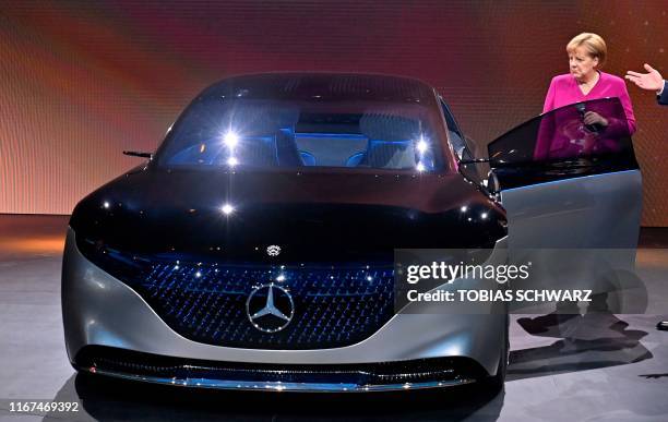 German Chancellor Angela Merkel stands next to a Mercedes Vision EQS car at the booth of Daimler as she tours the fair grounds after officially...