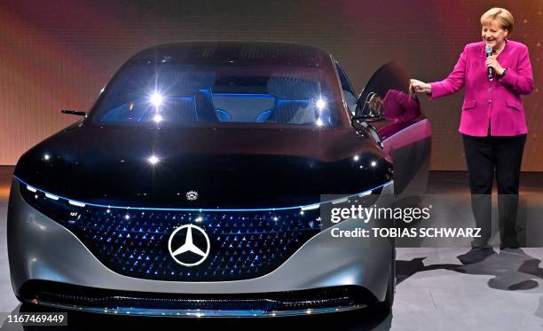 German Chancellor Angela Merkel stands next to a Mercedes Vision EQS car at the booth of Daimler as she tours the fair grounds after officially...