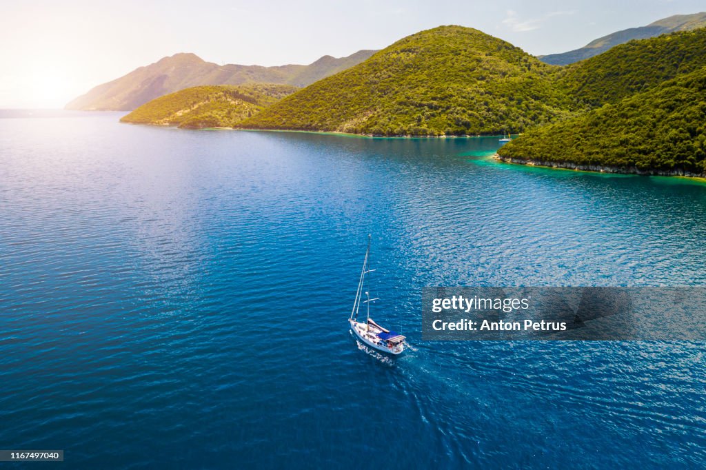 Lonely yacht with white sails in the sea. Summer vacation. Aerial view