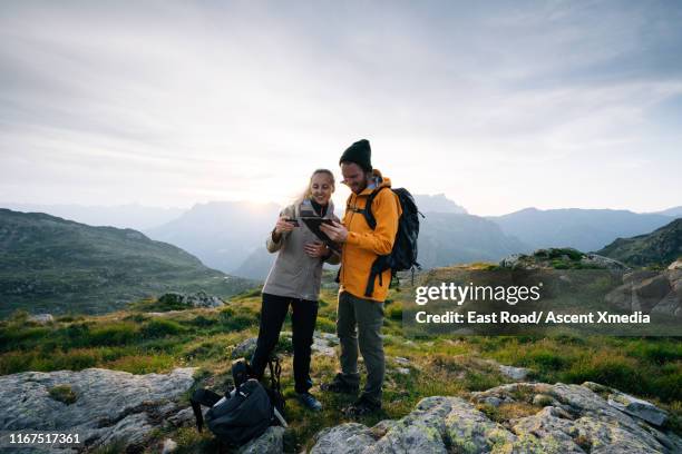 young couple check a photo or message on their phone on a high mountain pass - couple travel tablet stock-fotos und bilder