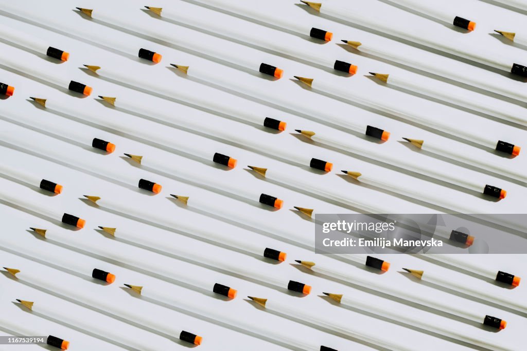 Row of white pencils lying on a white background